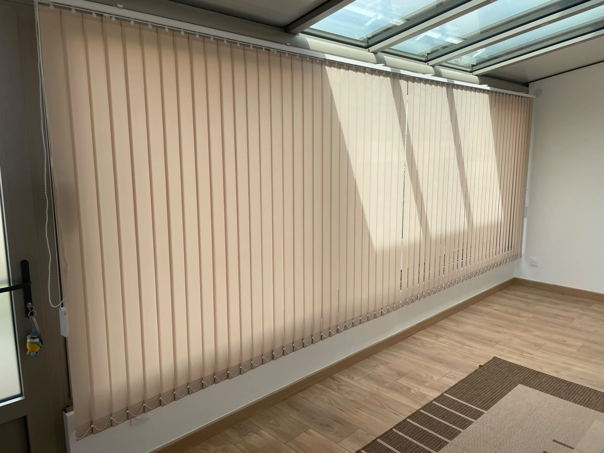 Stores verticaux beige installés devant une grande baie vitrée
